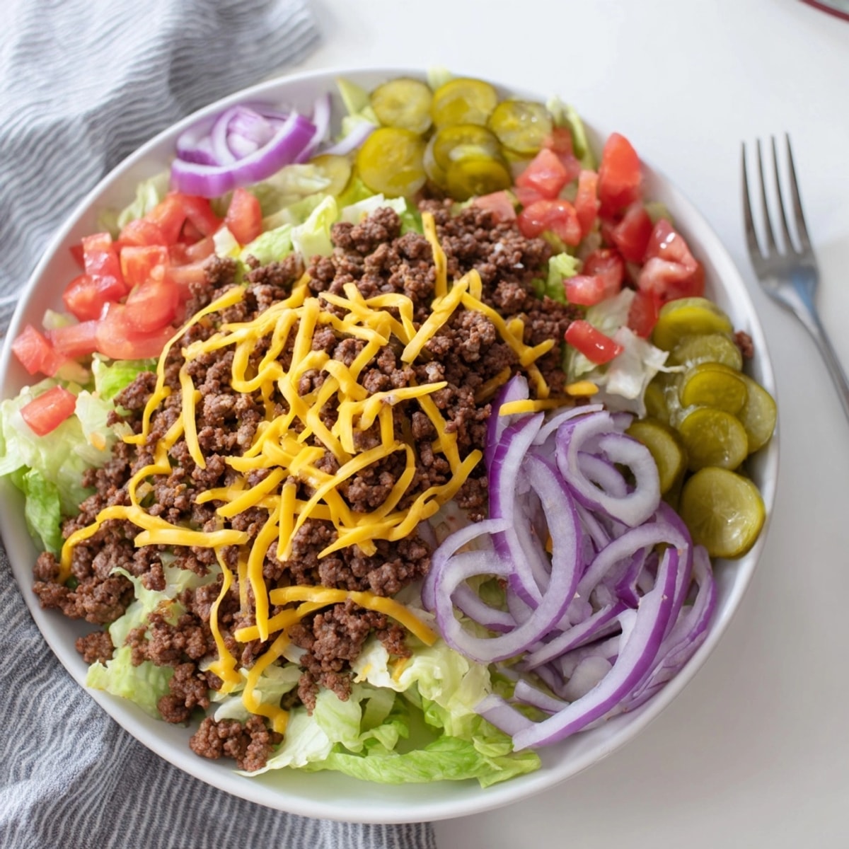 Making Big Mac Salad: Seasoned beef on lettuce, tomatoes, and cheddar; tangy dressing drizzled.