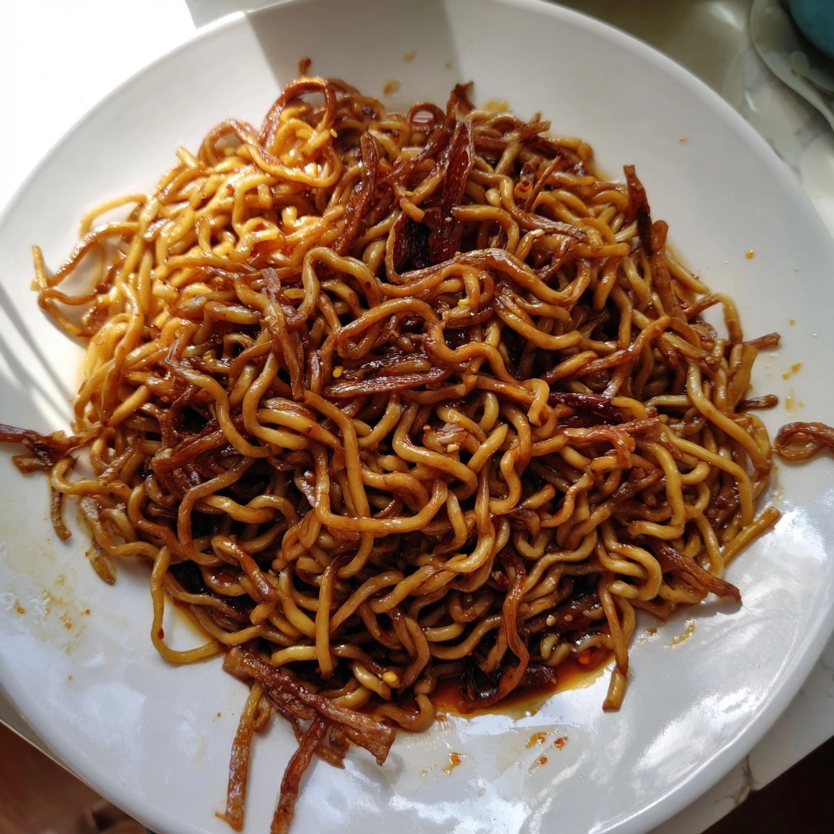 Golden, crispy scallions top a bowl of homemade Scallion Oil Noodles, illuminated beautifully.