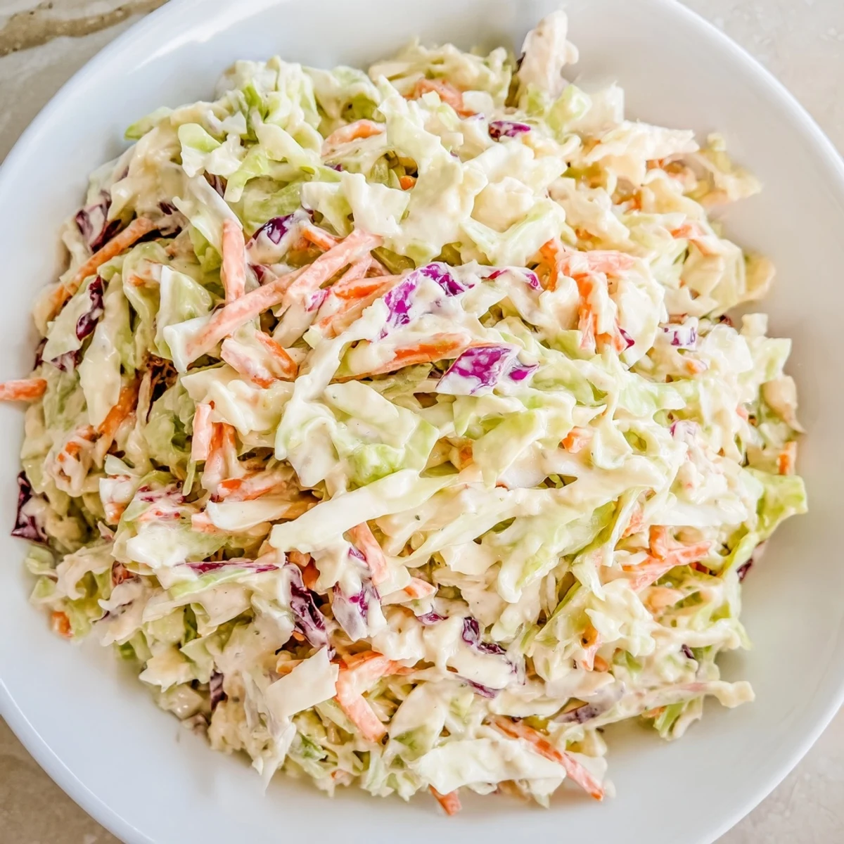 Creamy coleslaw, a vibrant, cold salad with visible shredded cabbage and carrots, ready to serve.