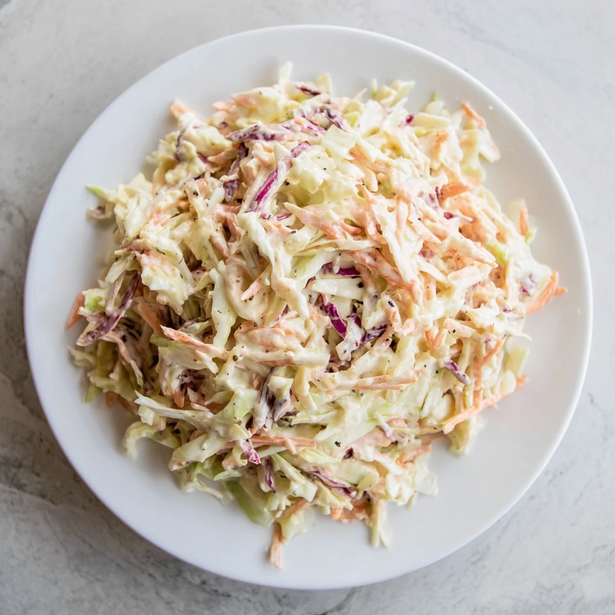 A close-up of creamy coleslaw in a bowl, showing the crisp vegetables and tangy dressing; an American classic.
