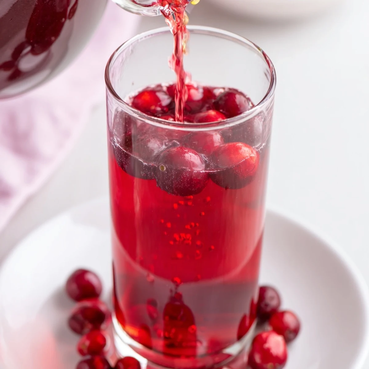 Bright red Cranberry Juice, freshly made with burst berries, looks beautifully tart in a glass.