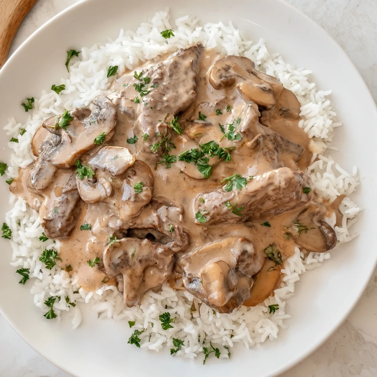 Creamy beef stroganoff served over rice, a classic Russian dish with a delightful, warm mushroom aroma.