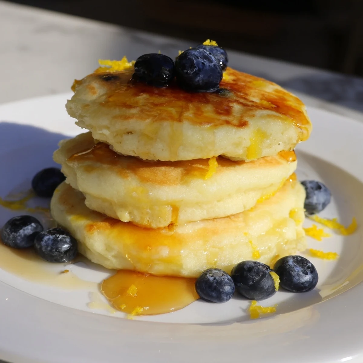 Breakfast plate of light and airy Lemon Ricotta Pancakes, ready to be enjoyed with a coffee.