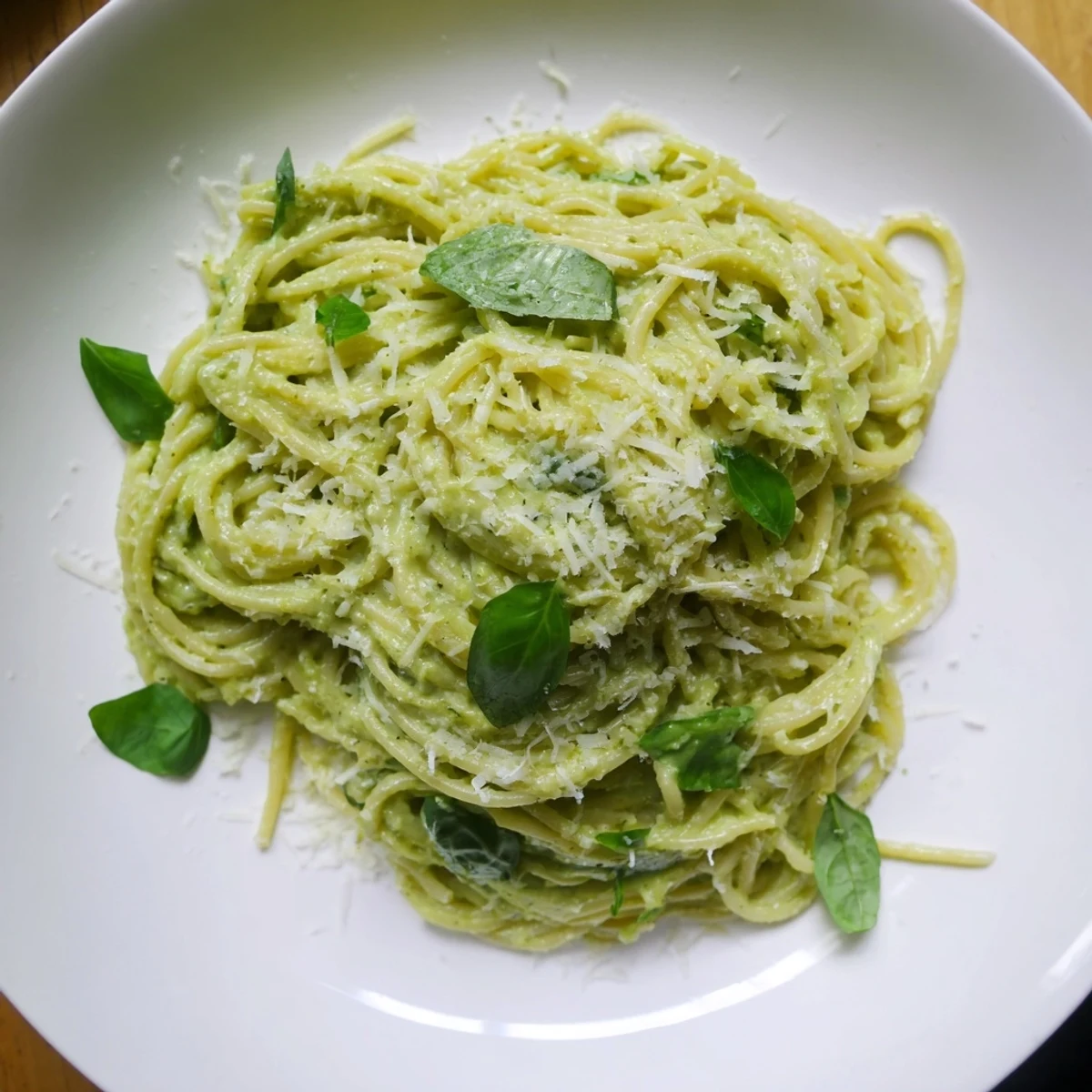 Creamy avocado pasta, a vibrant green dish topped with fresh basil and lemon zest.