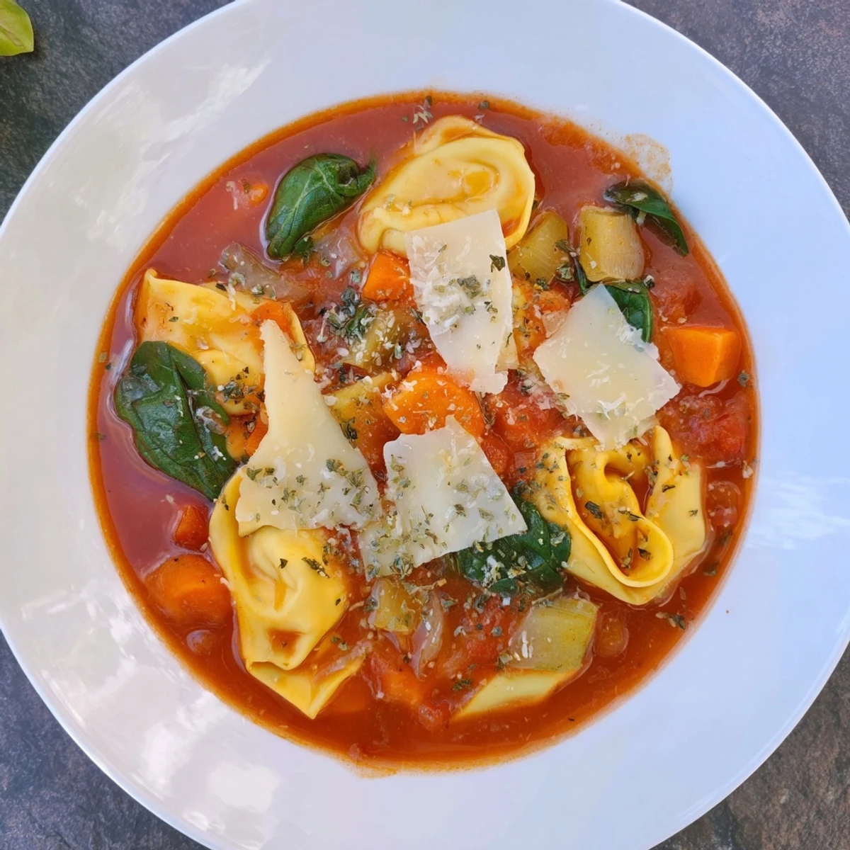 Close-up of hearty Tomato Tortellini Soup; the aroma of herbs and tomatoes fills the air.