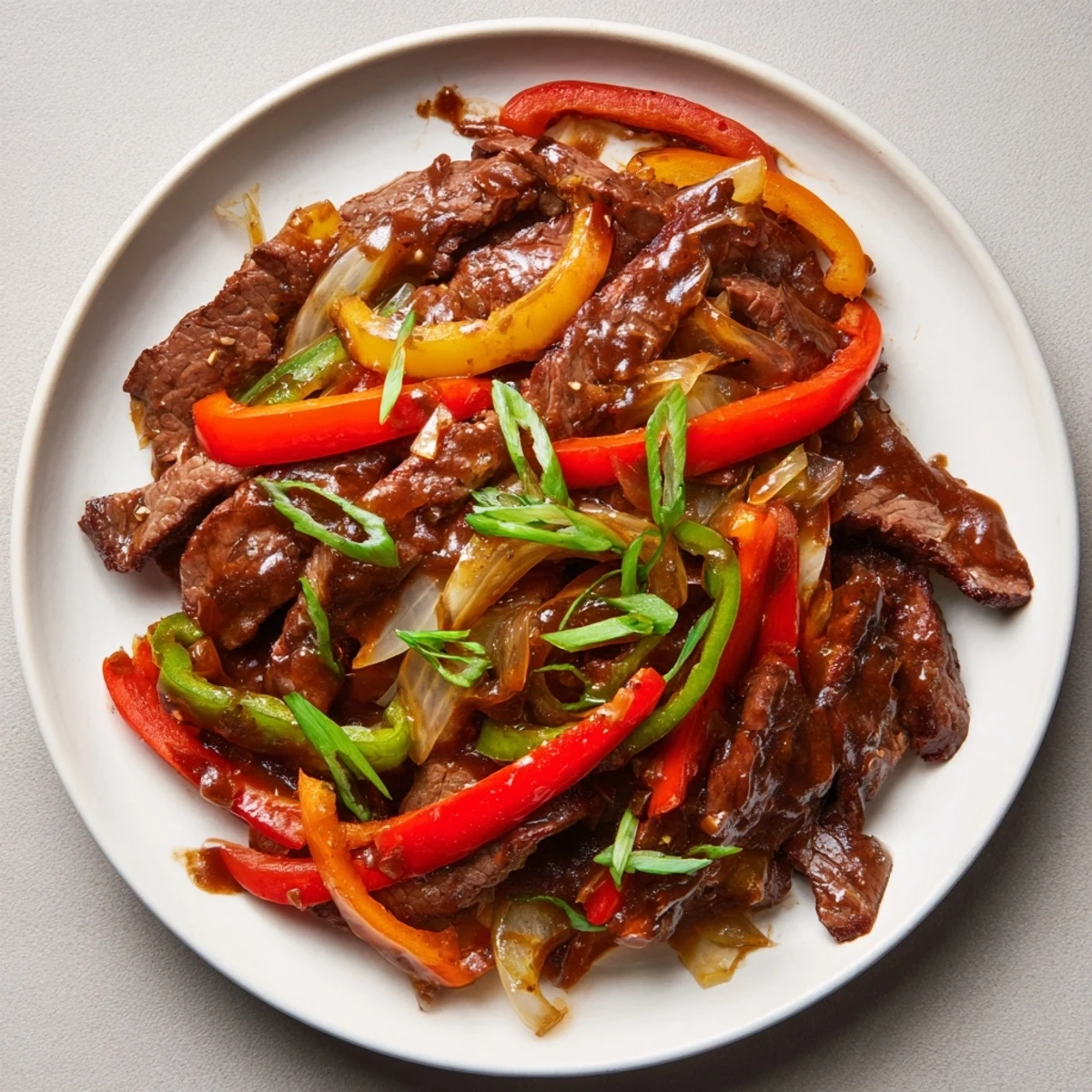 Pepper Steak stir-fry, sizzling with strips of beef coated in a savory black pepper sauce, served hot.