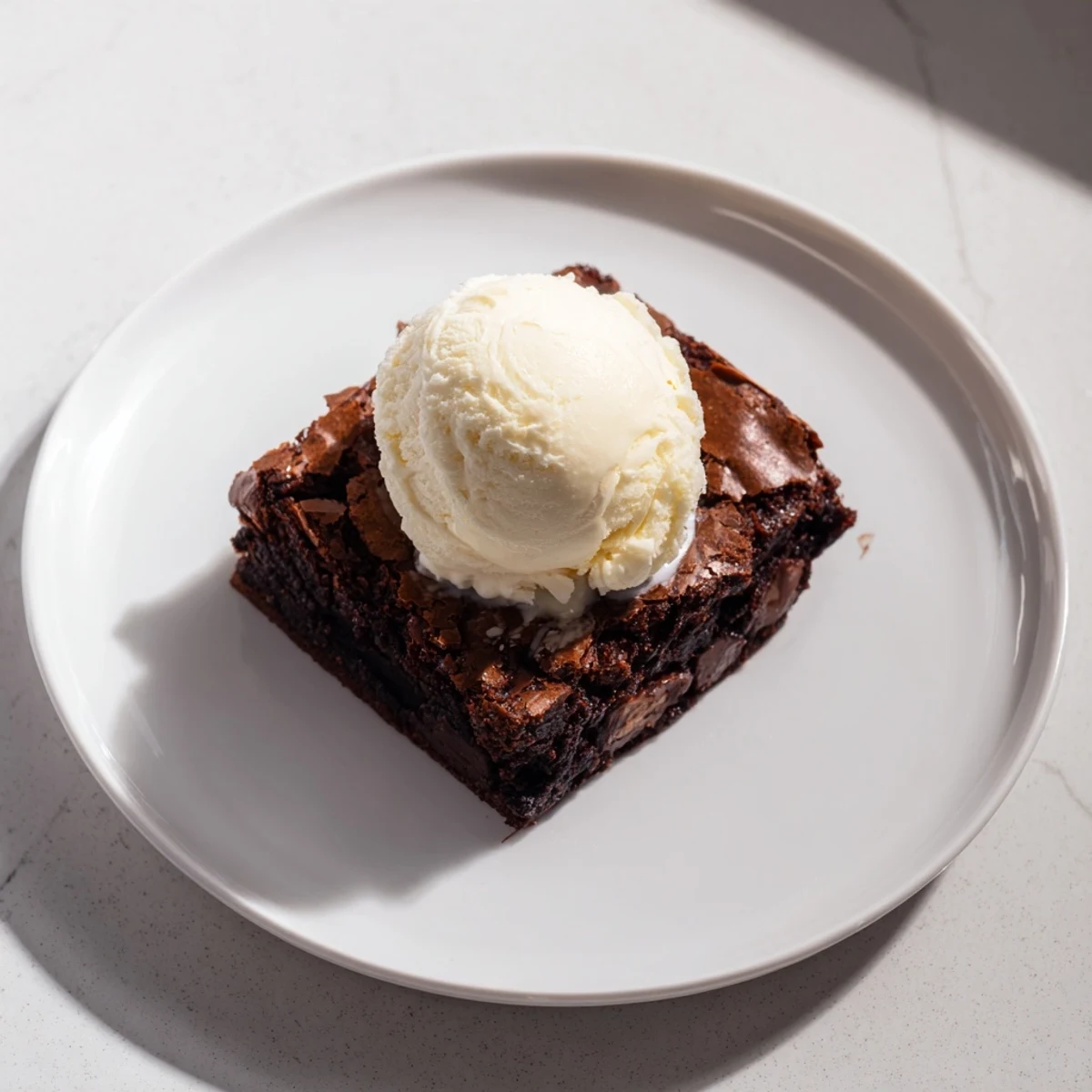 Indulge in this warm chocolate brownie, fresh from the oven, next to a creamy ice cream scoop.