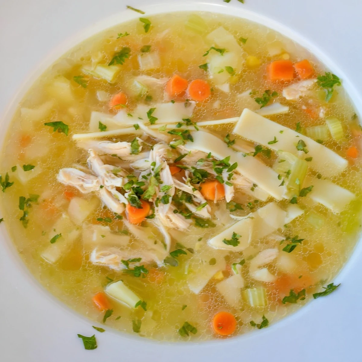 A close-up shot of hot Chicken Noodle Soup with fresh parsley, perfect for a cozy dinner.