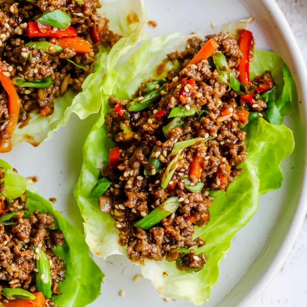 Close-up of delicious beef lettuce wraps, a flavorful Asian-inspired dish with optional lime wedges.