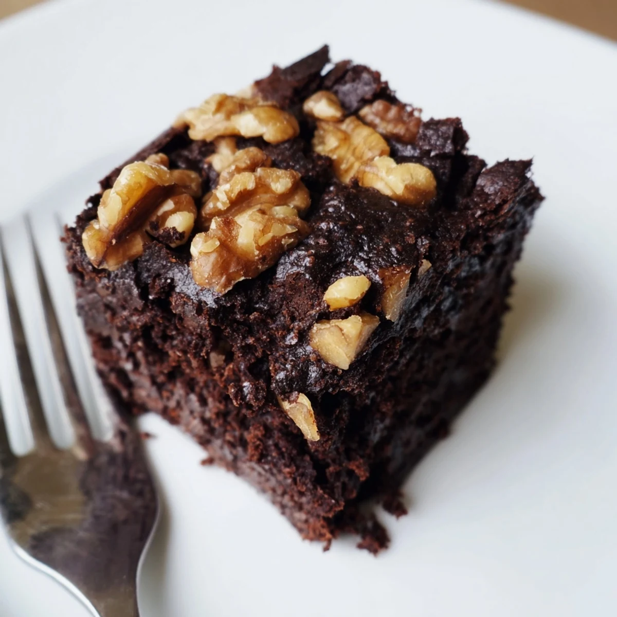 A close-up view of Chocolate Fudge Brownies with Chopped Walnuts featuring gooey chocolate centers and toasted nut pieces on a wooden board.