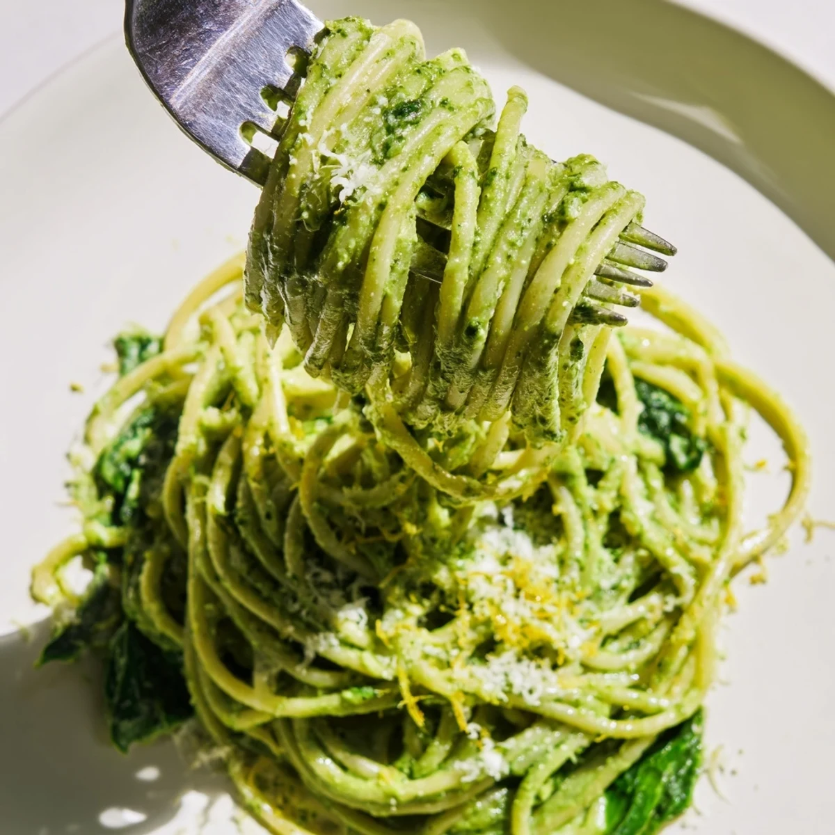 A bowl of Creamy Avocado and Spinach Spaghetti topped with Parmesan and lemon zest, ready to enjoy.