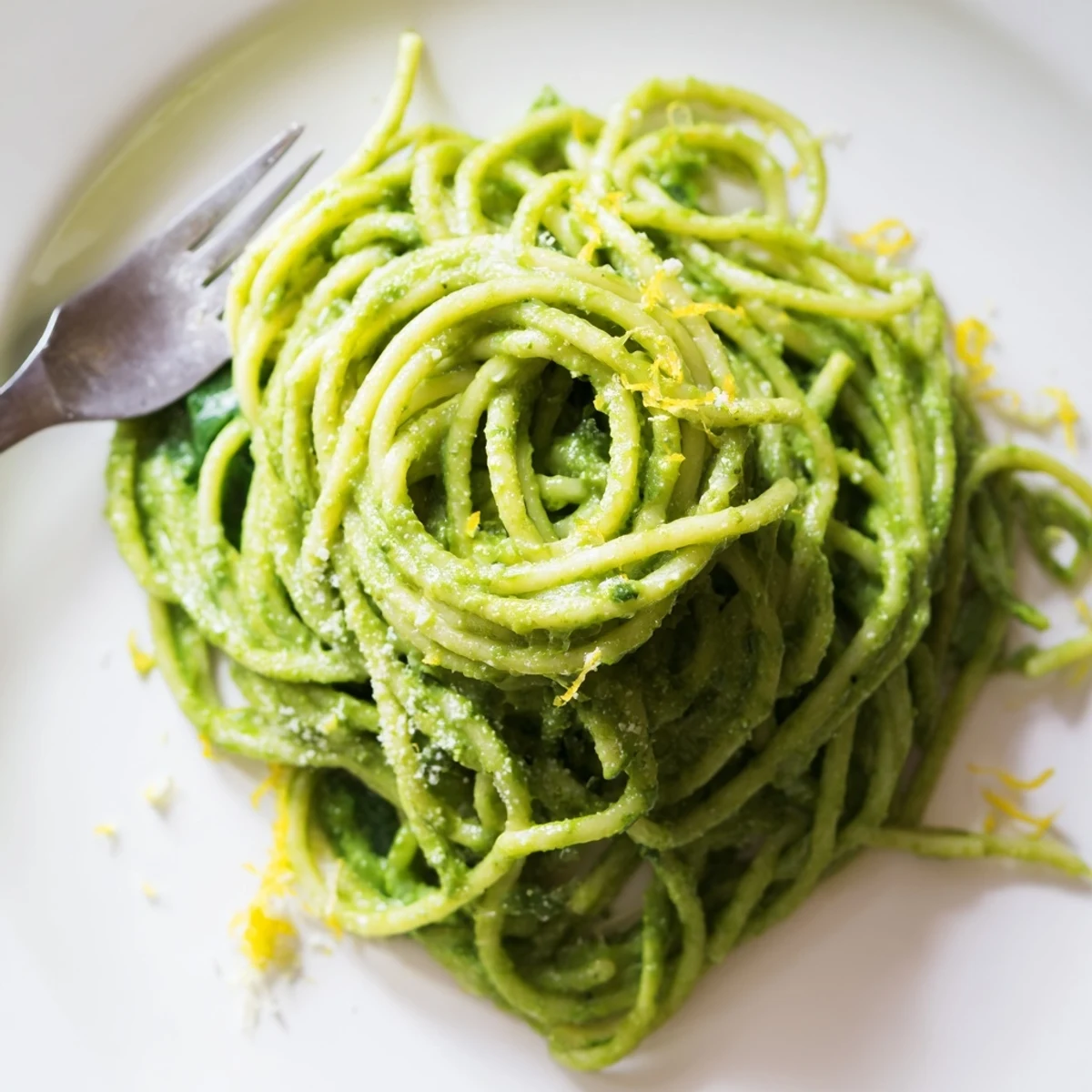 Creamy Avocado and Spinach Spaghetti twirled on a fork with vibrant green sauce glistening, served on a white plate.