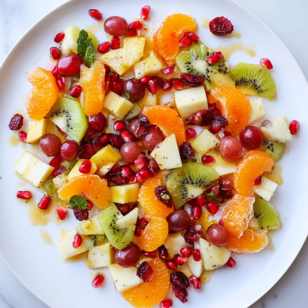 Fresh Winter Fruit Salad with Citrus Dressing served in a clear glass bowl, featuring vibrant segments of orange, sliced kiwi, and glistening pomegranate arils.