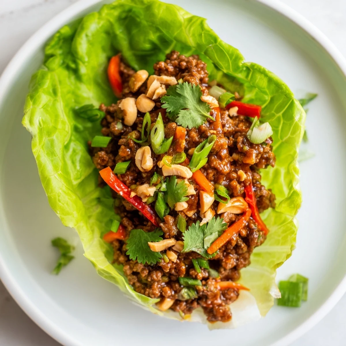 Savory Asian-inspired beef lettuce wraps drizzled with rich hoisin sauce, served in crisp greens with shredded carrots and a sprinkle of peanuts.