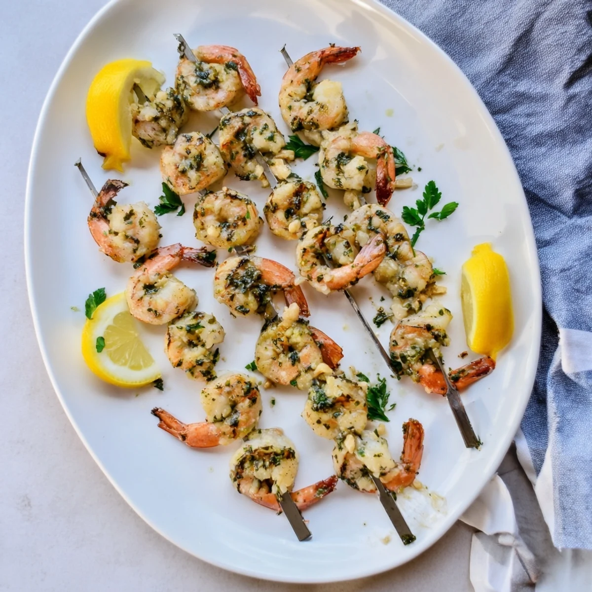 Golden Lemon Garlic Shrimp Skewers threaded on skewers, garnished with parsley and lemon, perfect for a quick summer dinner.