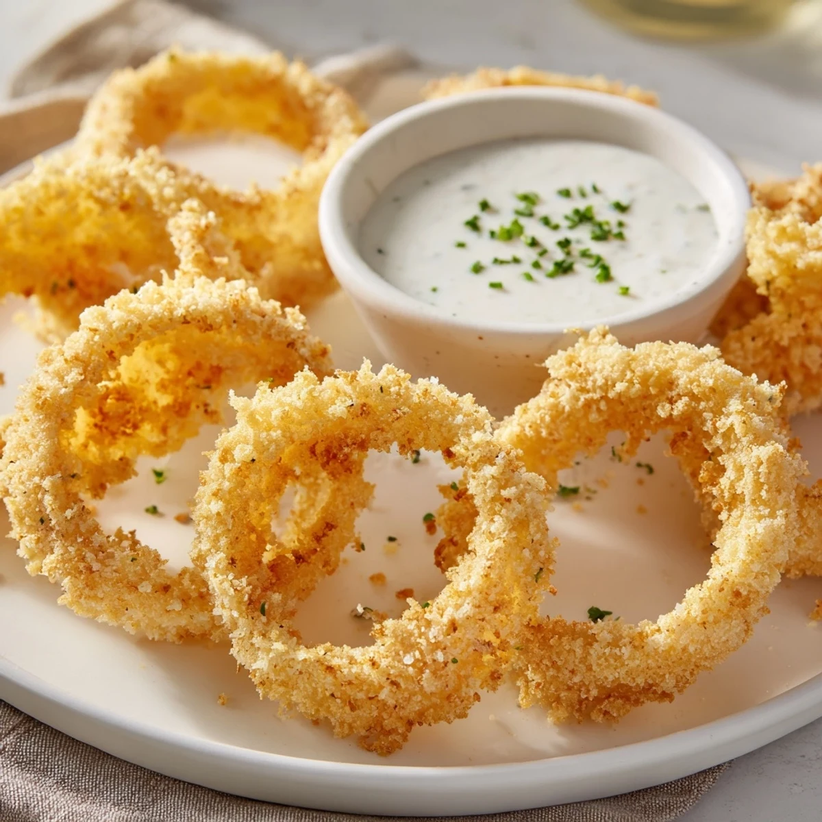 Golden-brown Touchdown Crispy Onion Rings with Ranch arranged on a platter with dipping sauce.