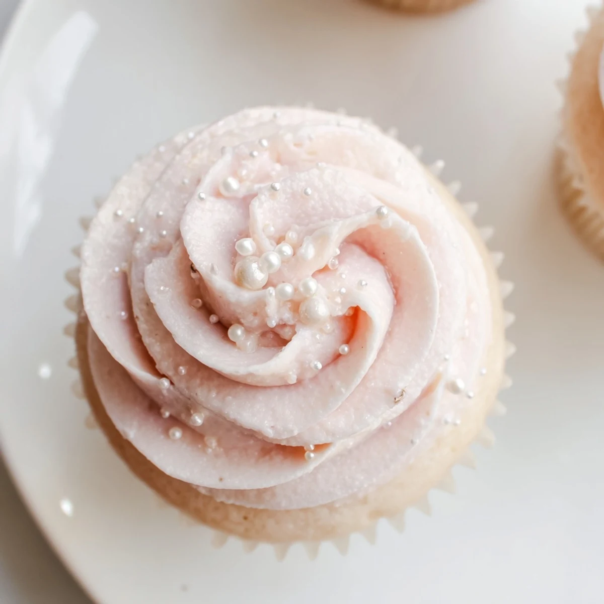 Twelve fluffy Pink Champagne Cupcakes with light pink buttercream frosting and edible pearls on top.