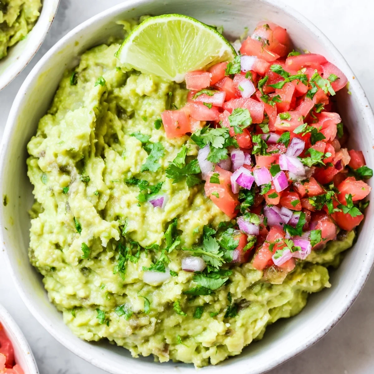 Close-up of Guacamole with Fresh Pico de Gallo and Lime, featuring lime wedges and a scoop of zesty dip for tacos.