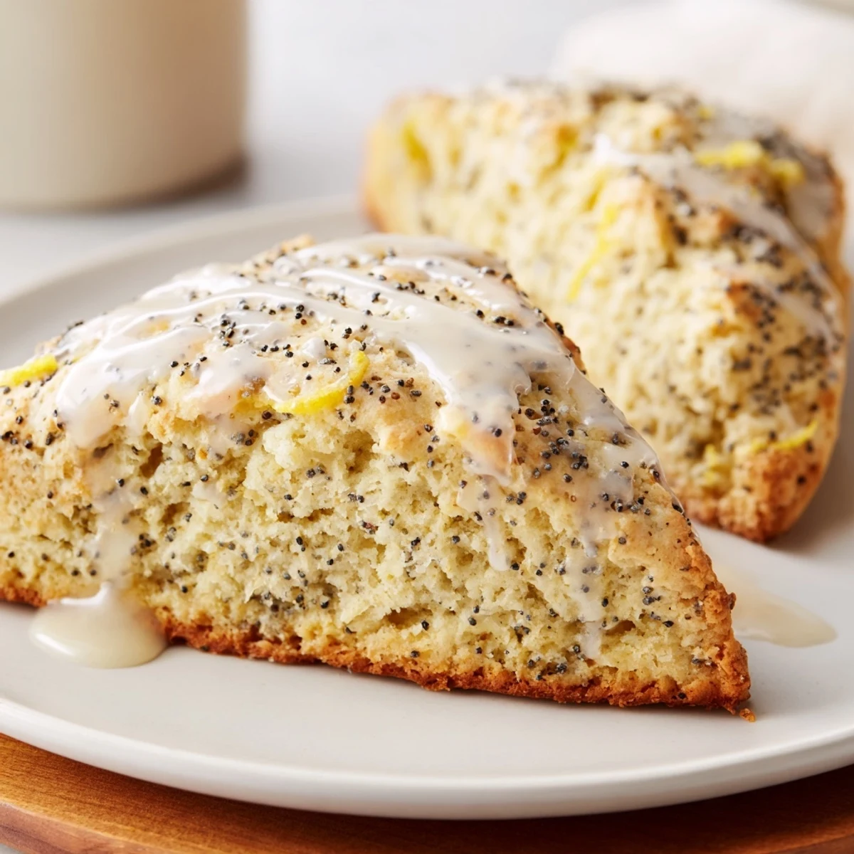 Freshly baked Lemon Poppy Seed Scones sit on a wire cooling rack, showing golden edges and a glossy lemon glaze.