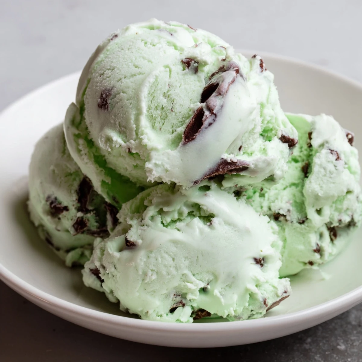 Serving suggestion for Green Mint Chocolate Chip Ice Cream in a waffle bowl with mint garnish on top.