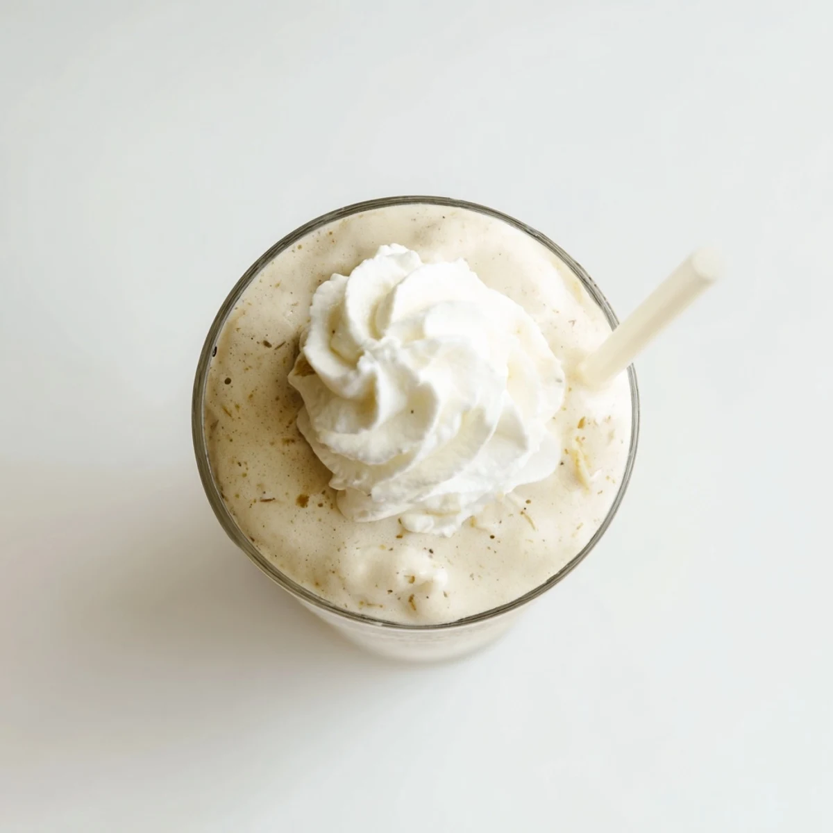 A tall glass of Vanilla Bean Frappuccino topped with whipped cream and a straw for sipping.