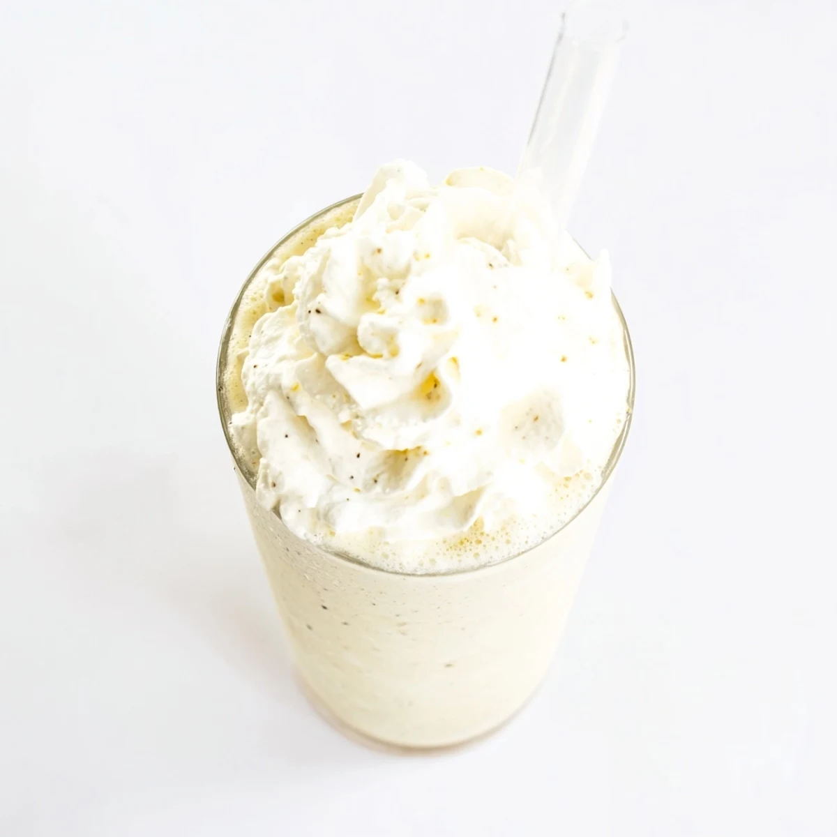 Vanilla Bean Frappuccino garnished with whipped cream, served in a tall glass on a wooden table.