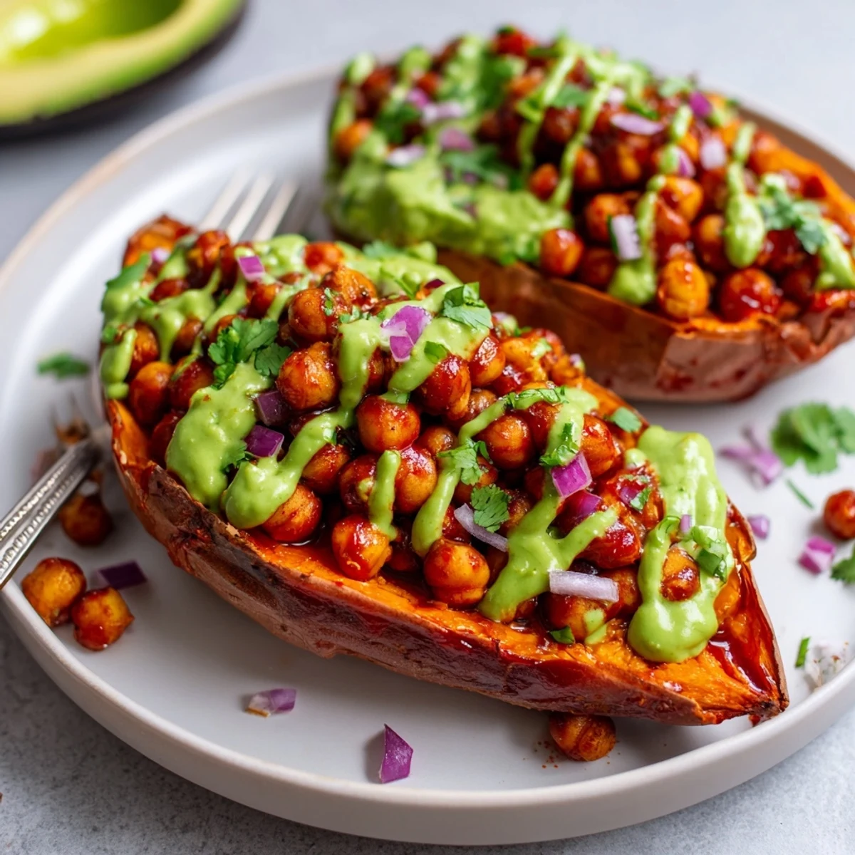 Sizzling BBQ chickpeas and creamy avocado drizzle star in this easy Vegan BBQ Chickpea Sweet Potatoes recipe served with jalapeños.