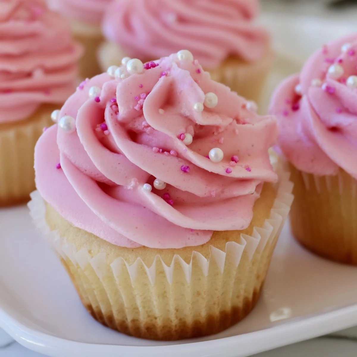Piped swirls of soft pink frosting top each Girl Baby Shower Cupcake, ready to be served at the celebration.