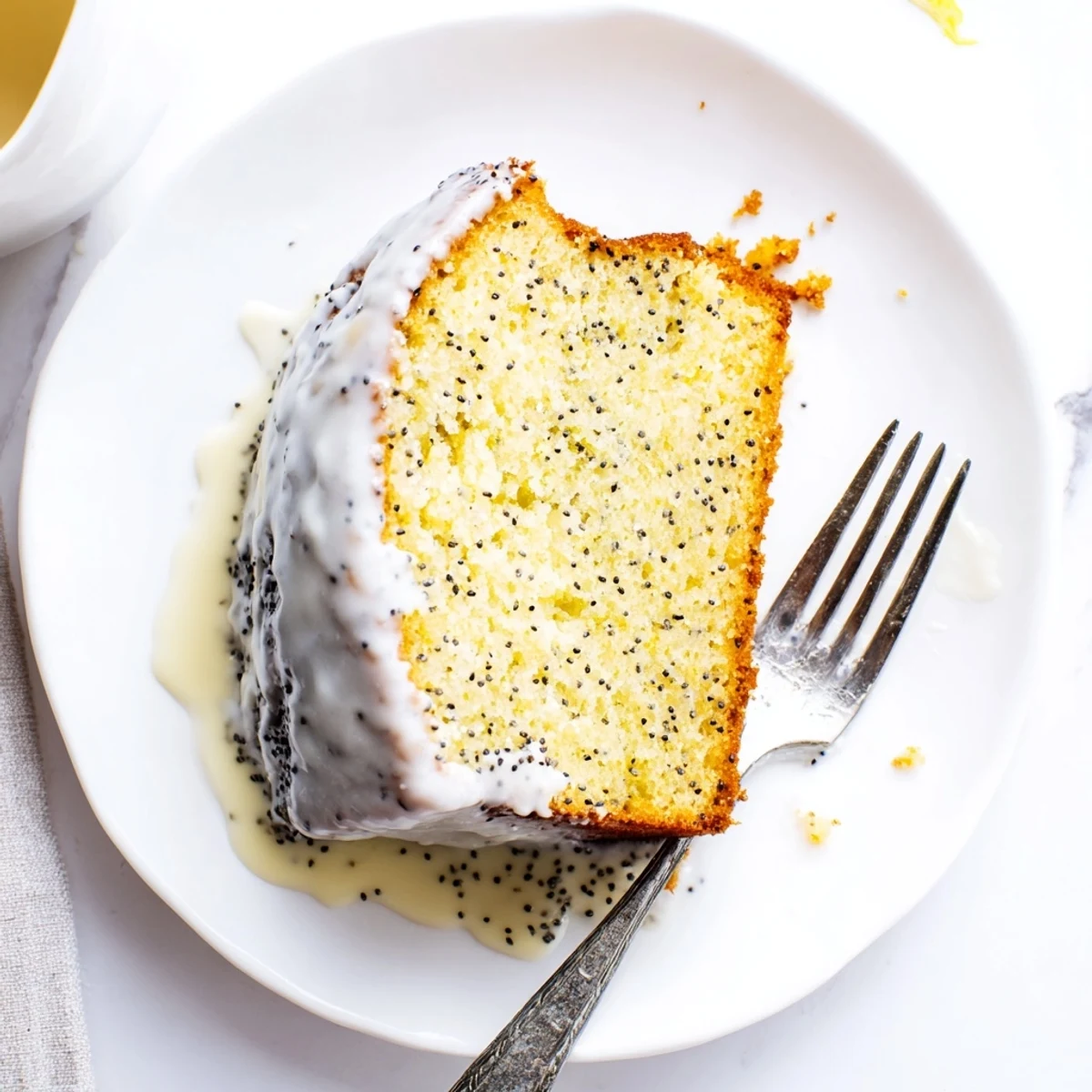 Golden glazed Lemon Poppy Seed Cake with a tender crumb, displayed on a wooden serving board.