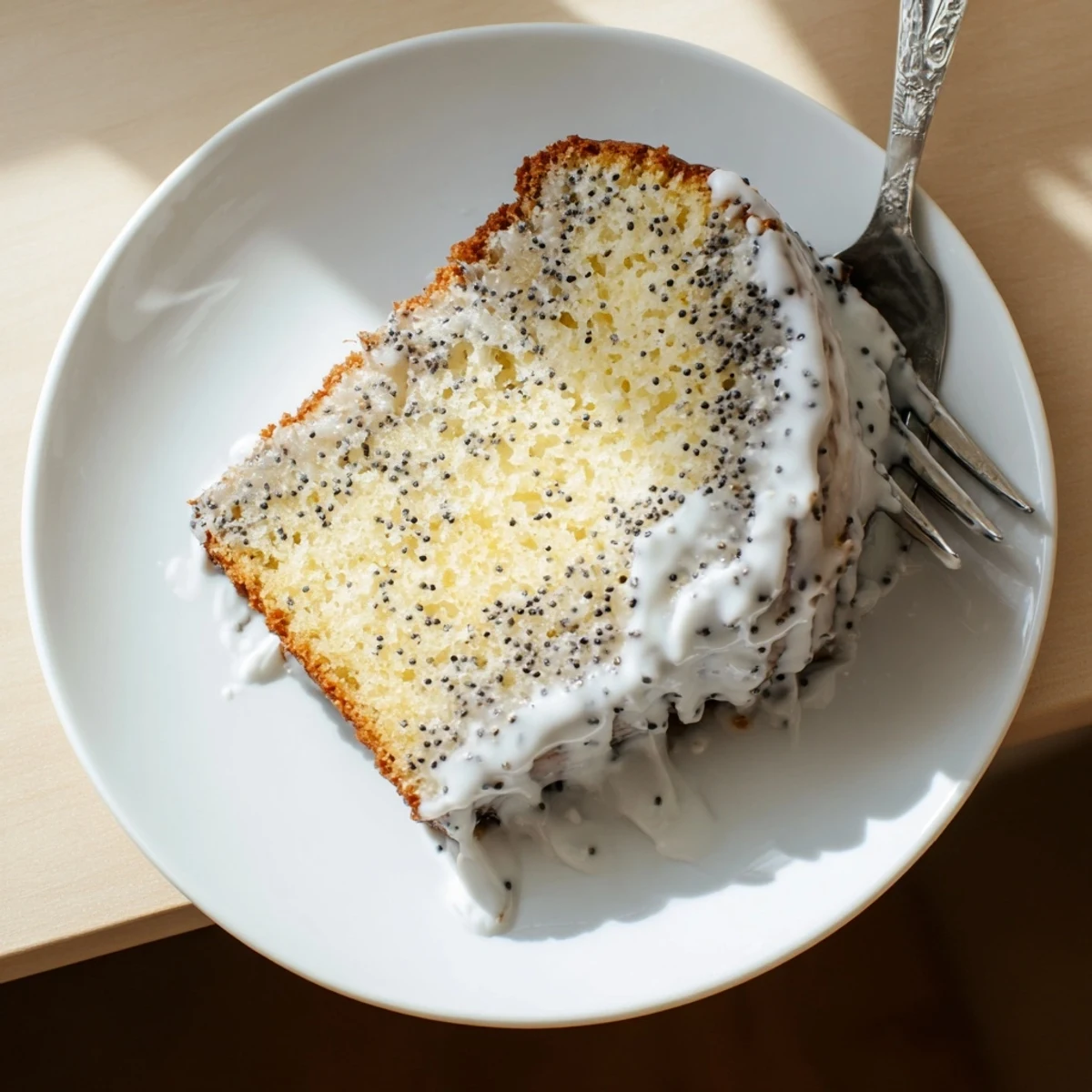 Overhead view of Lemon Poppy Seed Cake on a white plate with fresh lemon slices and tea.