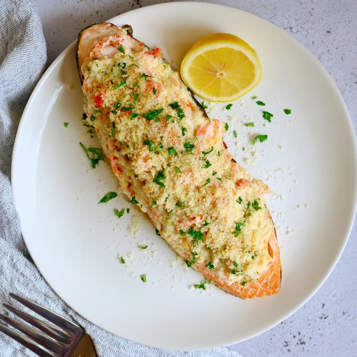 Golden-baked Crab & Shrimp Stuffed Salmon fillets served with lemon wedges on a white plate.  