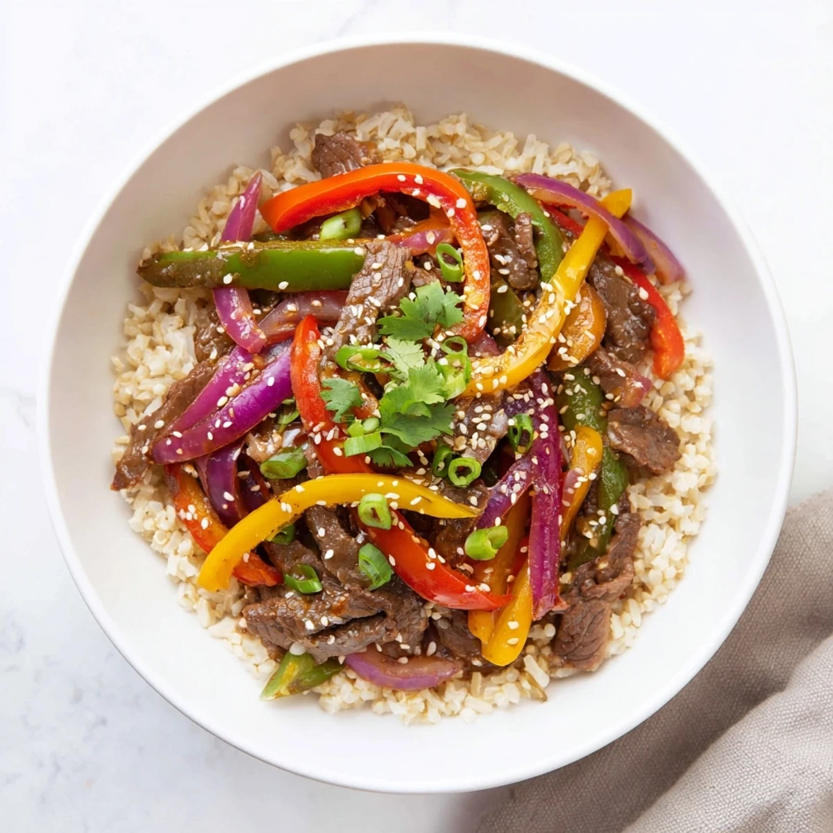 Healthy Beef and Pepper Rice Bowl features brown rice topped with savory garlic-ginger sauce and garnishes. 