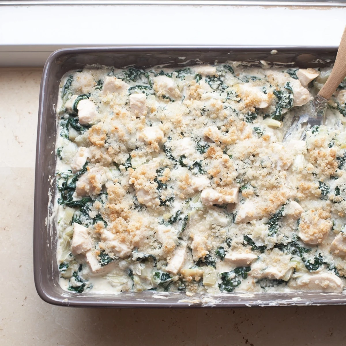 Steamy high protein spinach and artichoke chicken casserole fresh from the oven with golden breadcrumb crust