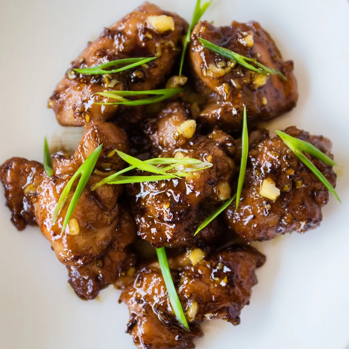 Golden brown Mongolian chicken pieces glazed in a rich sweet and savory caramelized sauce with fresh green onion garnish