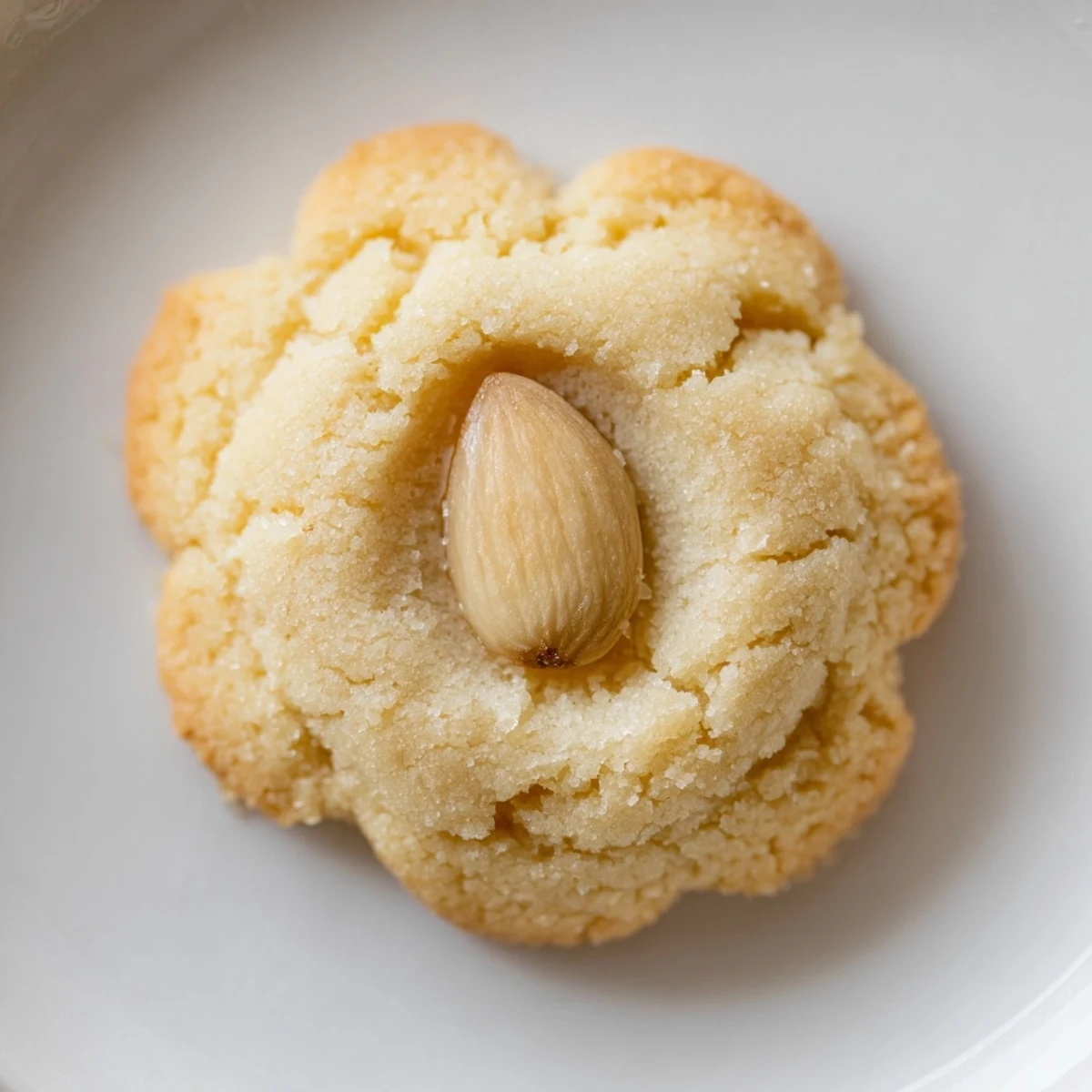 Golden Chinese almond cookies with whole almond centers arranged on a wooden cutting board