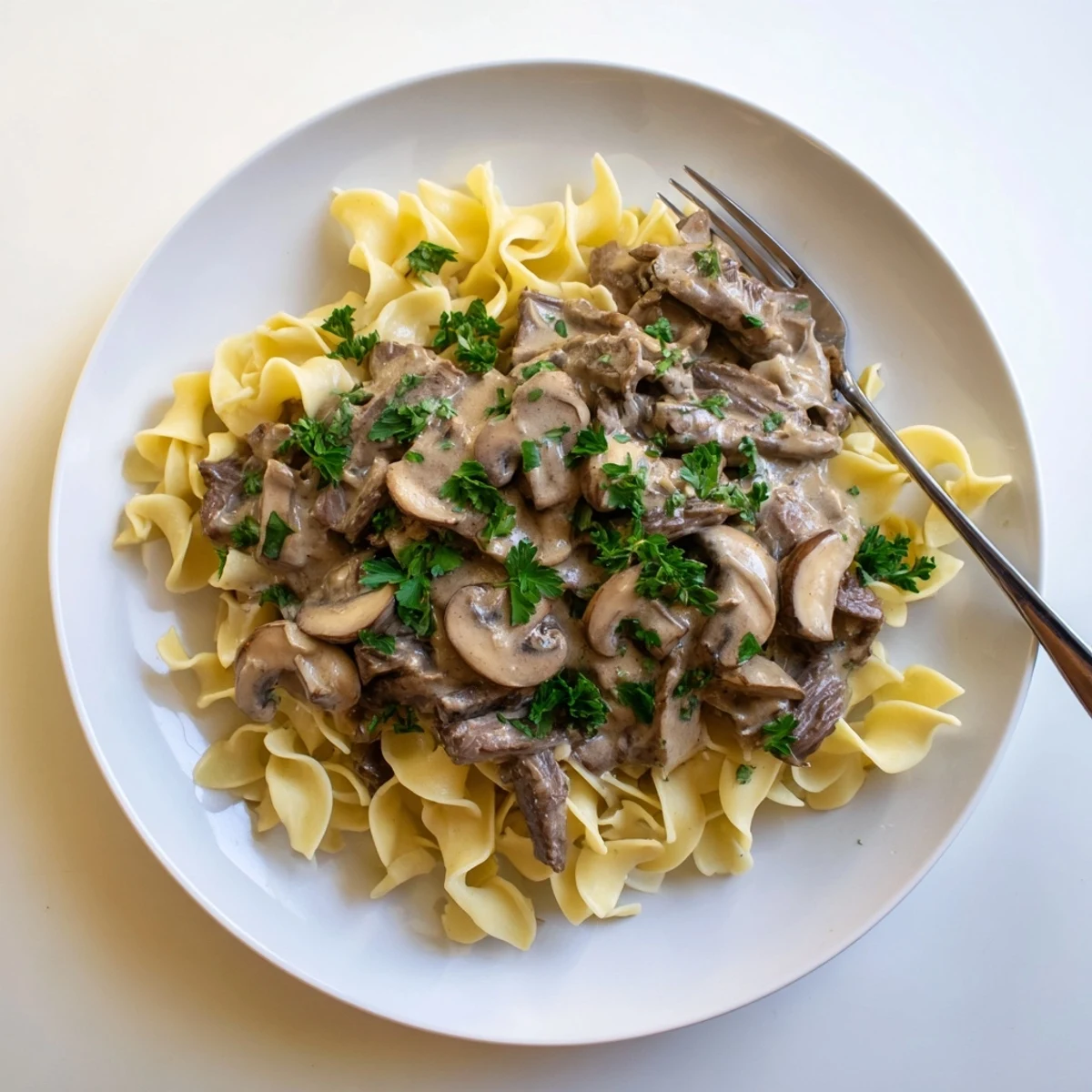 Creamy beef and mushroom stroganoff served over tender egg noodles with fresh parsley garnish