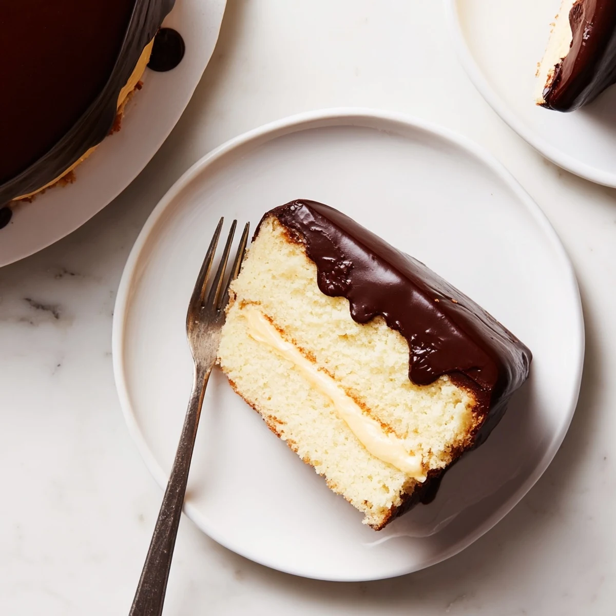 Golden Boston Cream Cake with glossy chocolate topping and creamy vanilla center cross-section view