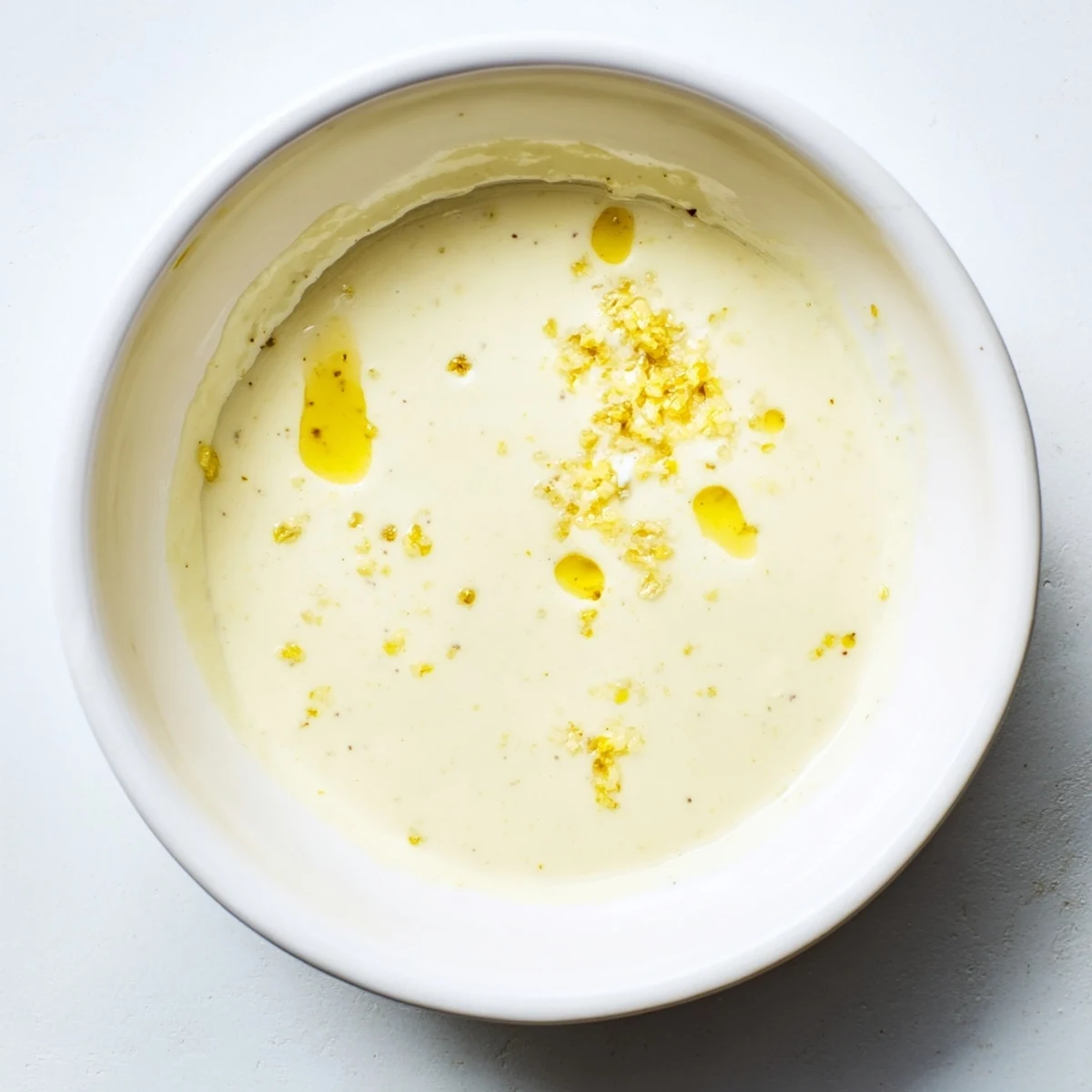 Smooth bright yellow vinaigrette poured from glass jar onto crisp vegetable salad