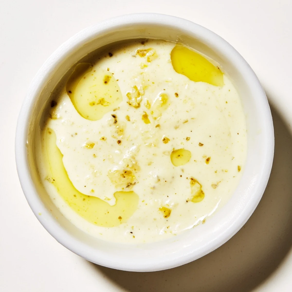 Thick homemade lemon dressing with olive oil emulsion and visible lemon zest