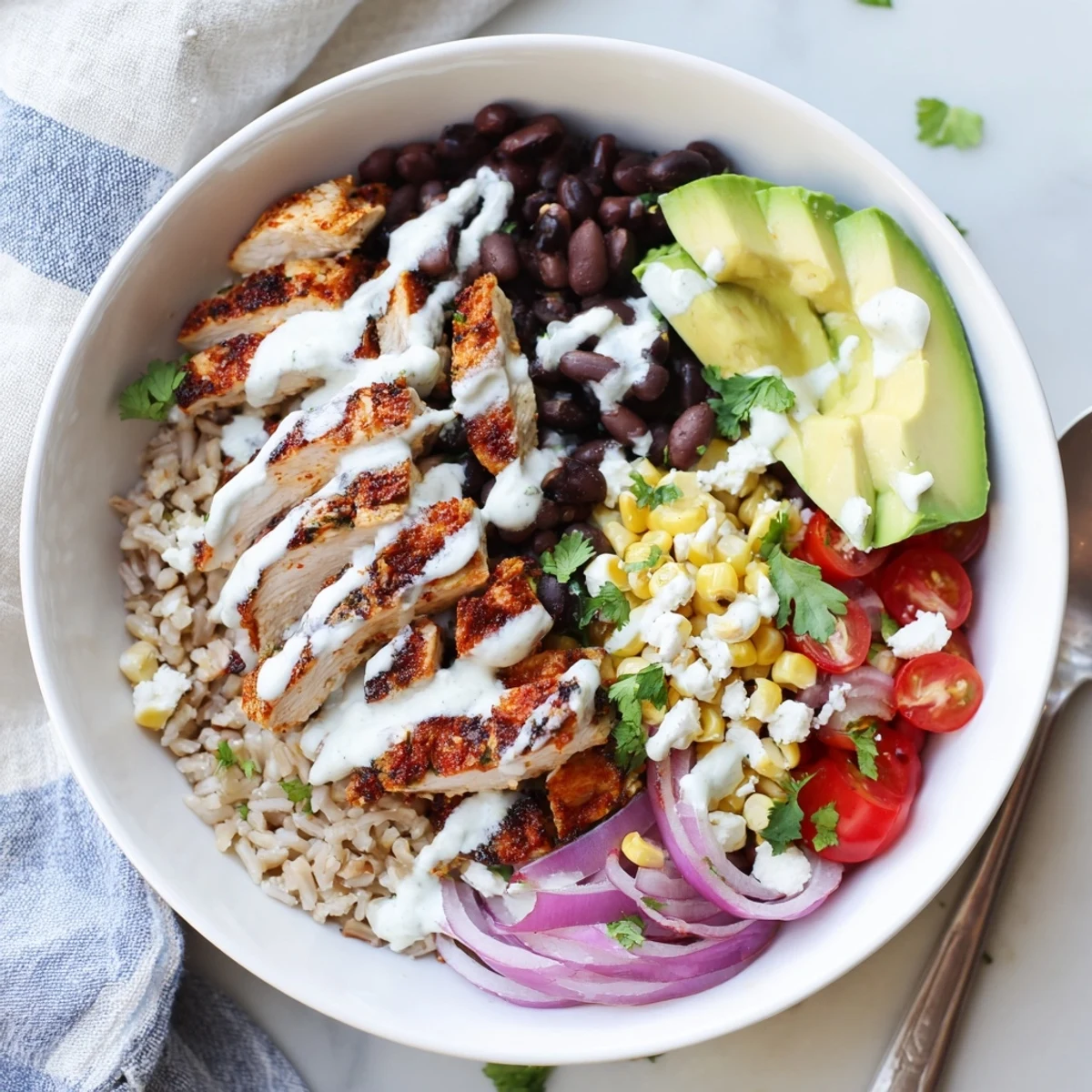 Sliced spiced chicken atop protein packed street corn chicken bowl with fresh cilantro garnish