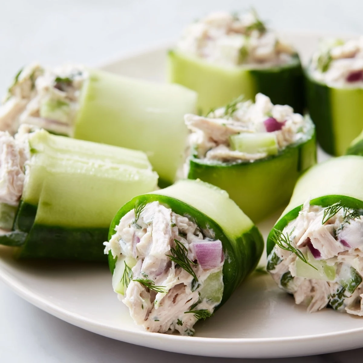 Crisp cucumber roll ups stuffed with savory chicken salad and topped with baby spinach leaves
