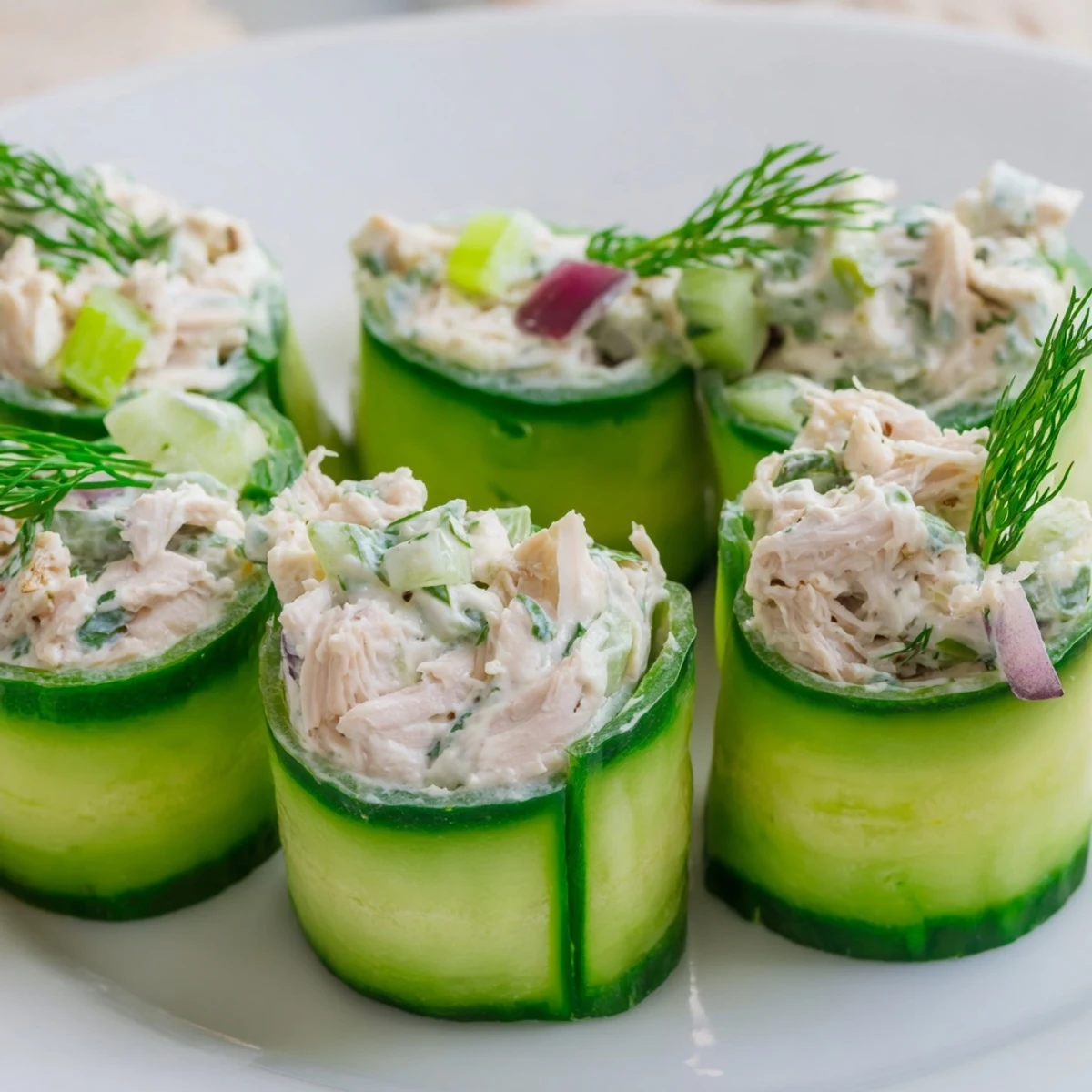 Gluten-free appetizer featuring chicken salad cucumber roll ups arranged on a rectangular dish