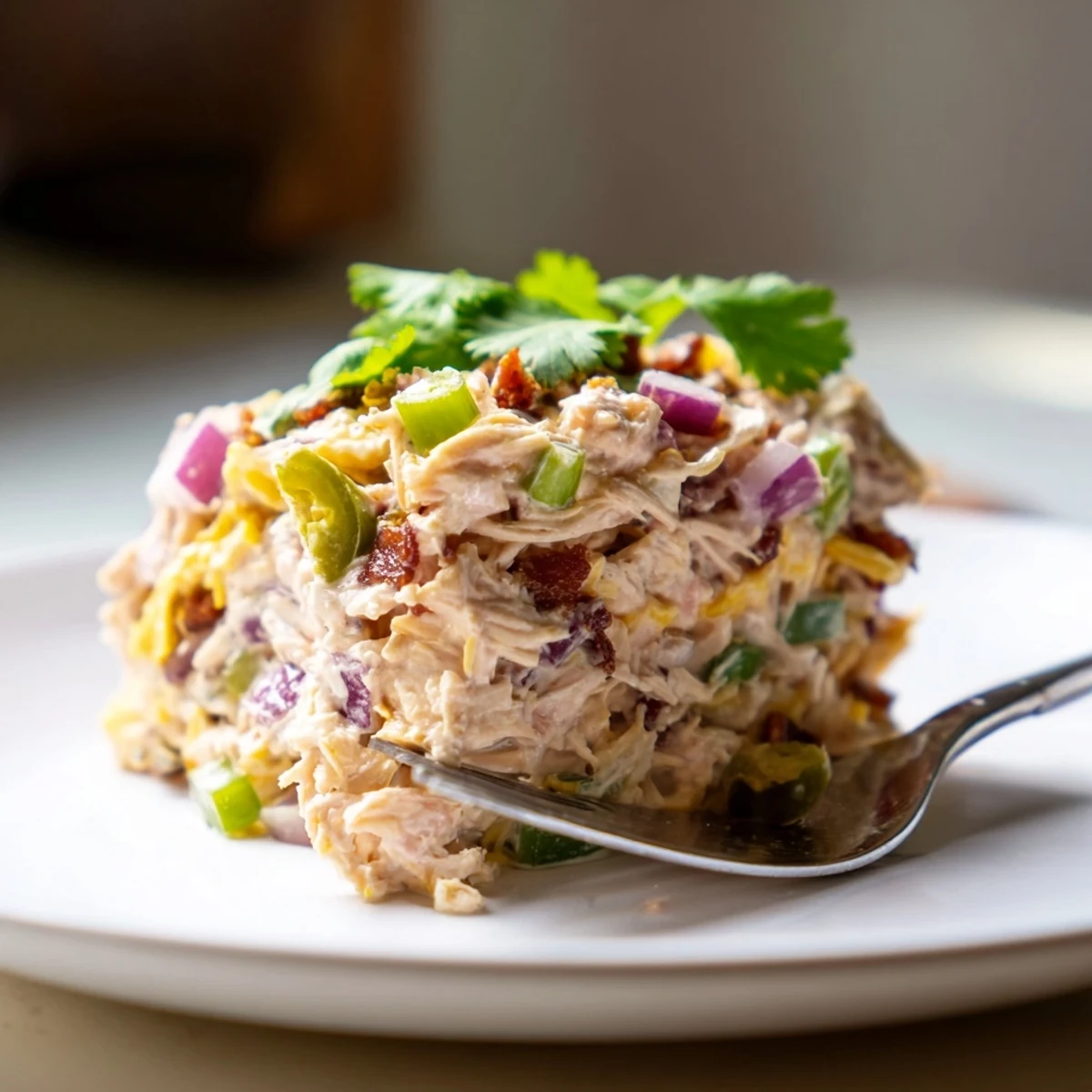 Low carb chicken salad bowl with melted cheddar, diced jalapenos, and smoky bacon crumbles on a rustic wooden table