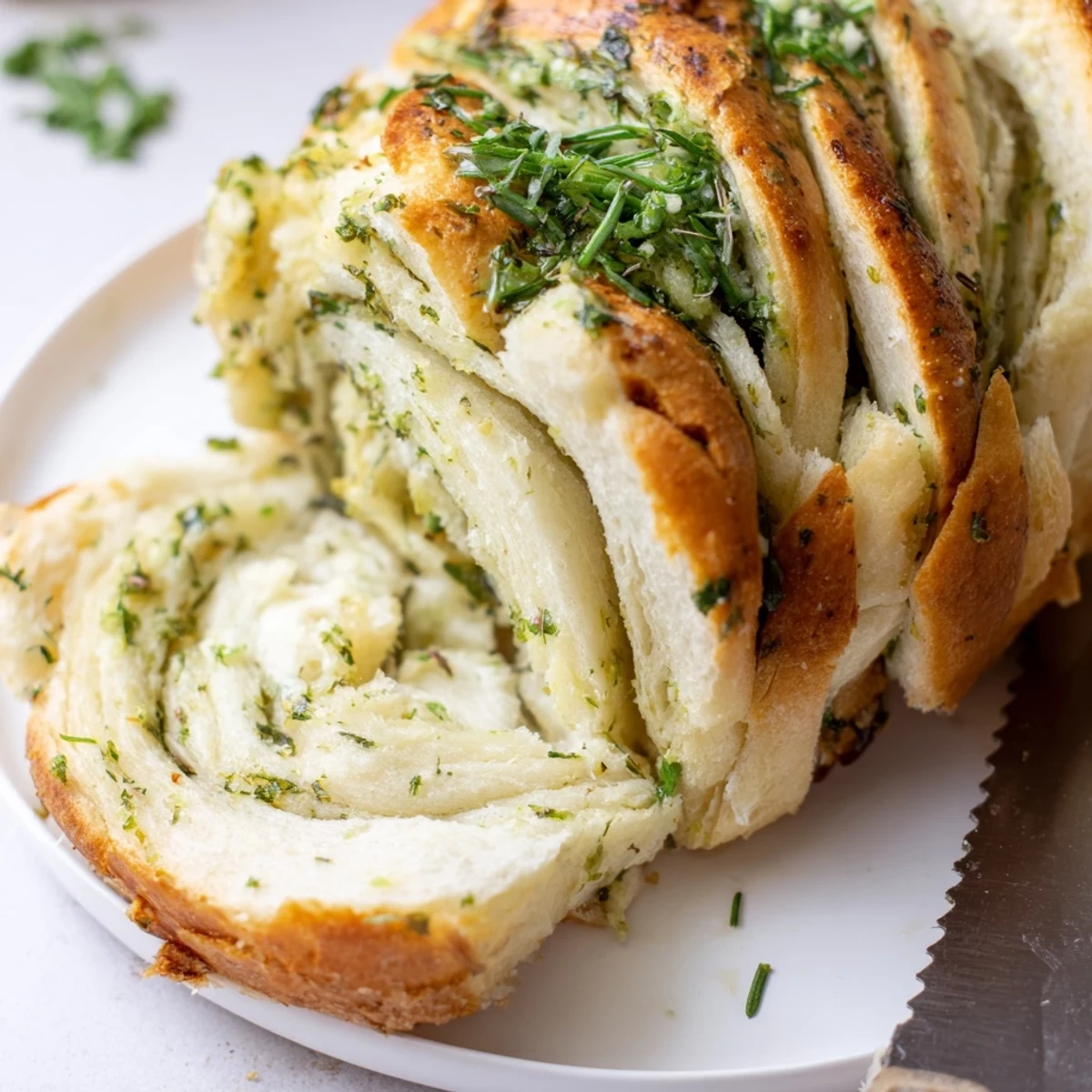 Homemade garlic and herb bread pulled apart revealing steam rising from the buttery herb-infused layers