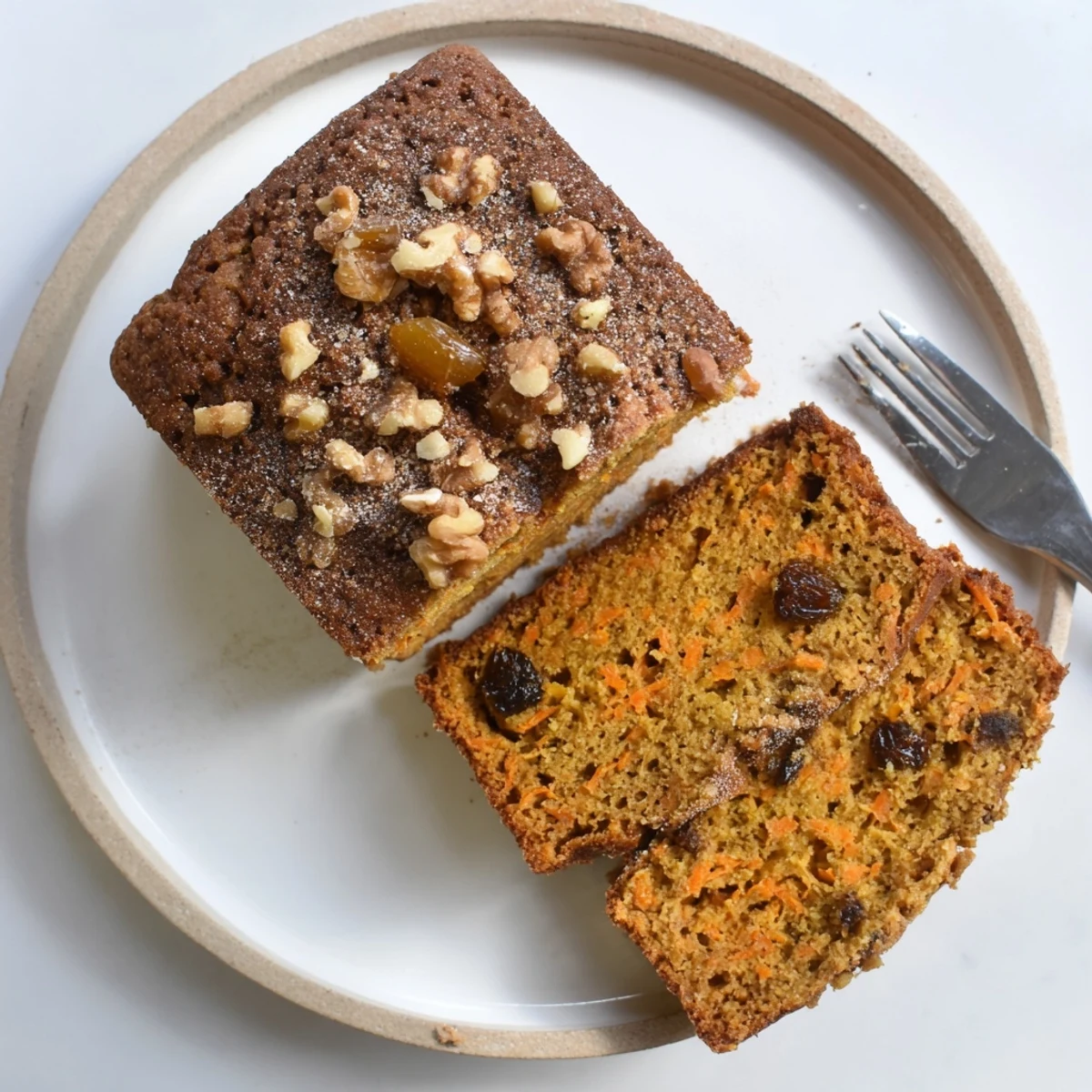 Golden brown carrot cake banana bread loaf topped with chopped walnuts on a wooden cutting board