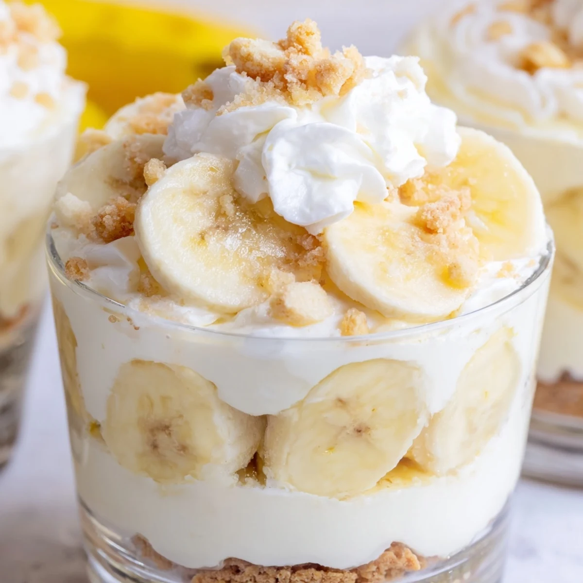 Creamy no bake banana pudding cheesecake cups layered with vanilla wafer crumbs and fresh banana slices