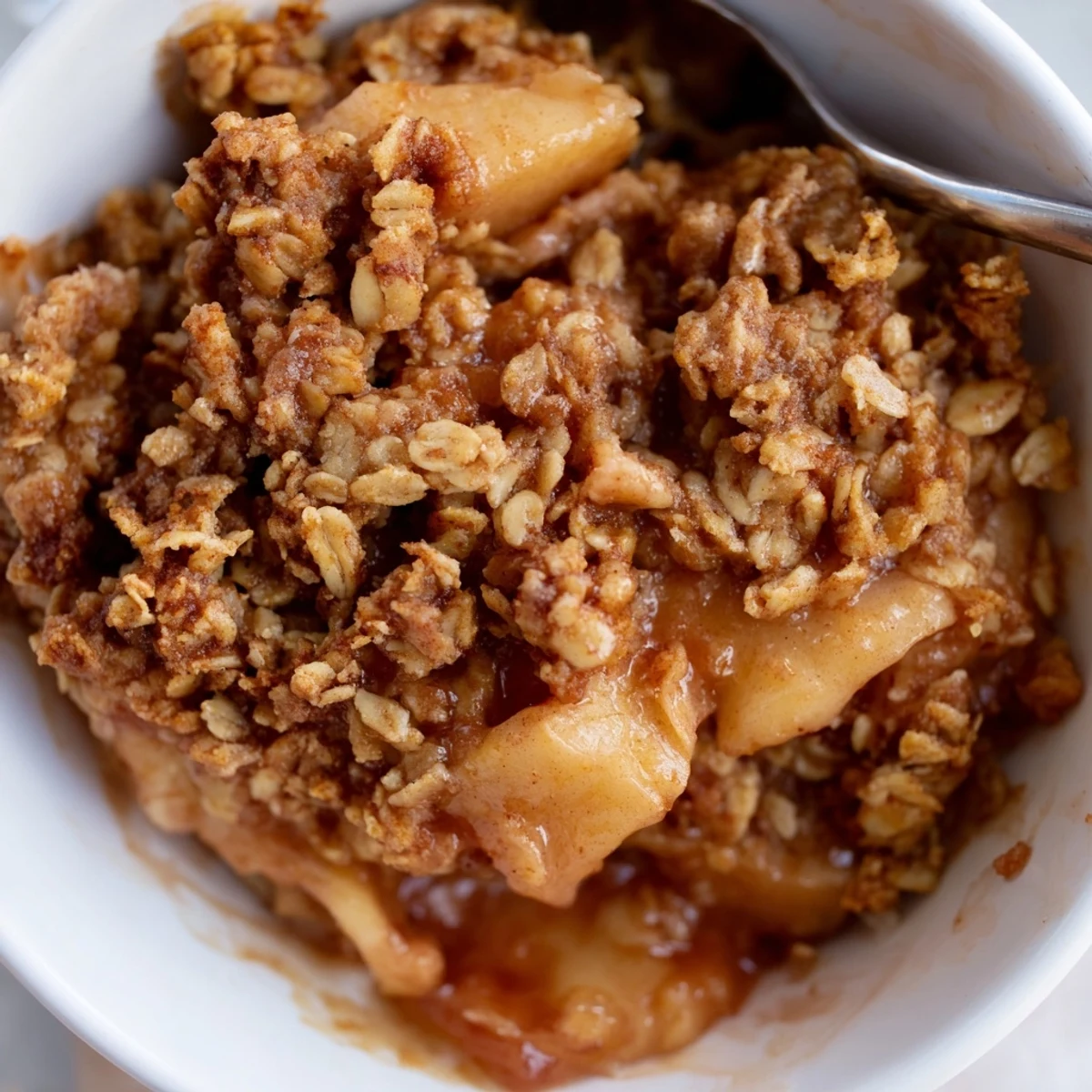 Creamy vanilla ice cream melting over a steaming scoop of homemade crockpot apple crisp with crispy oat topping