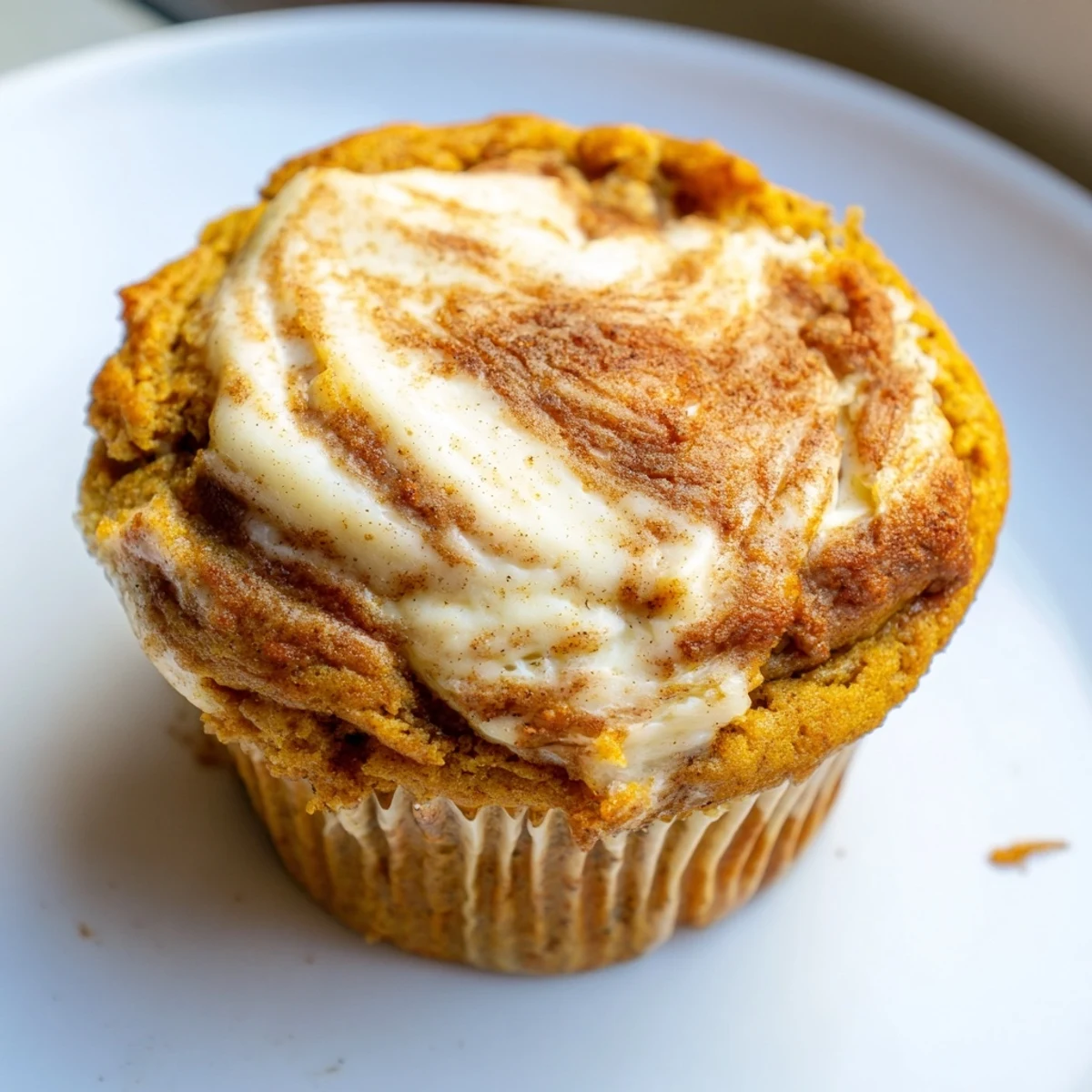 Moist chai pumpkin cheesecake muffins topped with creamy swirled frosting