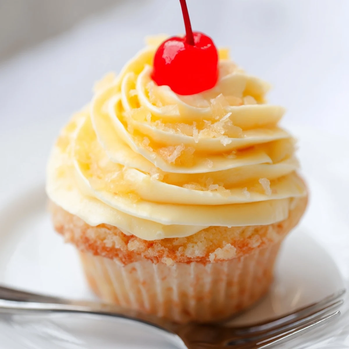Moist pineapple Dole Whip Cupcakes piped with airy whipped frosting on a white plate