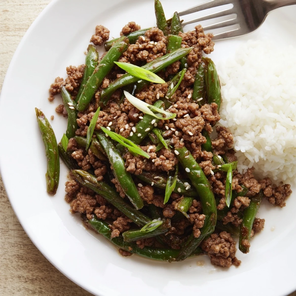 Bowl of Chinese Green Beans and Ground Beef with sesame garnish, steamed rice